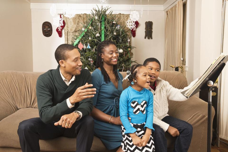 december holidays  family sitting on a couch in a living room singing christmas carols