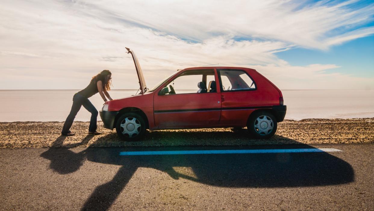 Woman stranded due to car trouble on a desert road.