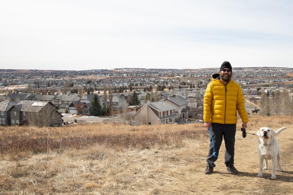 Panorama Hills resident Tarv Bajwa poses for a photo with his dog Rex with a view of the city's northwest suburbs at Hidden Valley Park in Calgary on Monday. For many, the suburbs are a great place to raise a family and pets.