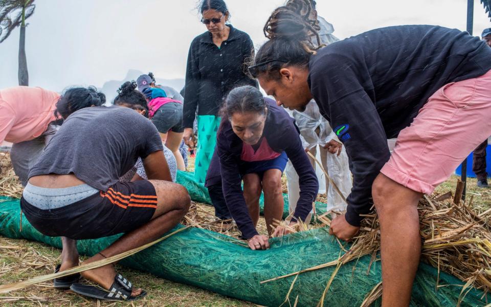 Local volunteers make absorbent barriers of straw stuffed into fabric sacks to contain oil from the MV Wakashio. -  LAURA MOROSOLI/EPA-EFE