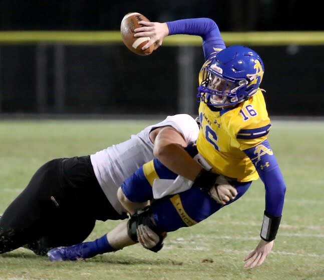 LA PUENTE, CALIF. - SEP 9, 2021. Bishop Amat quarterback Tobin O'Dell is brought down for a loss by Servite defensive tackle Mason Graham on Thursday night, Sep. 9, 2021. (Luis Sinco / Los Angeles Times)