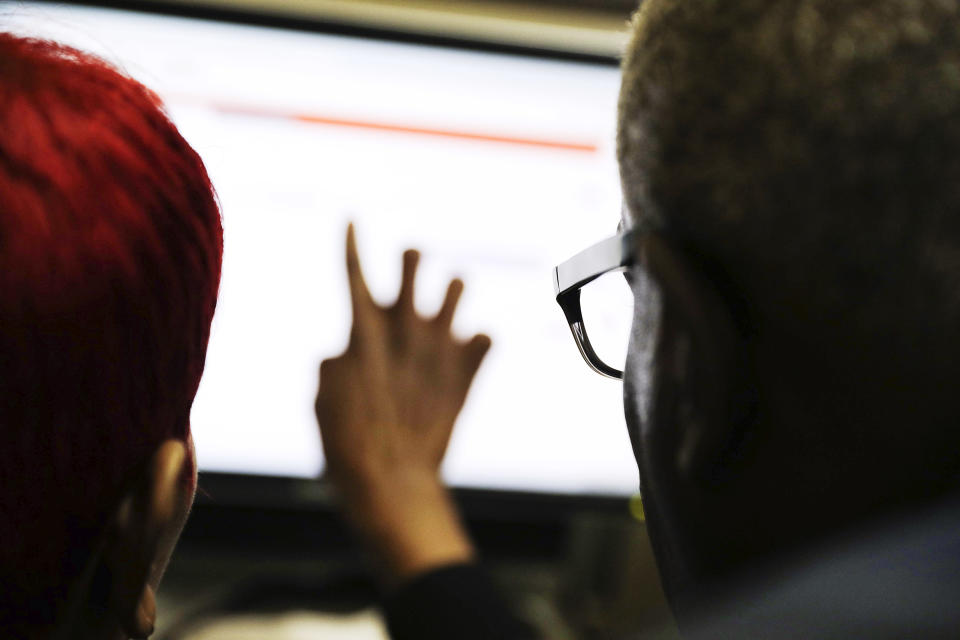 FILE - In this March 3, 2016, file photo, two people work on a computer in Atlanta. Researchers who study misinformation predict it will get worse leading up to this year's presidential vote. Misinformation and disinformation can take the form of false news stories and photos and videos that have been doctored or presented without context. (AP Photo/David Goldman, File)