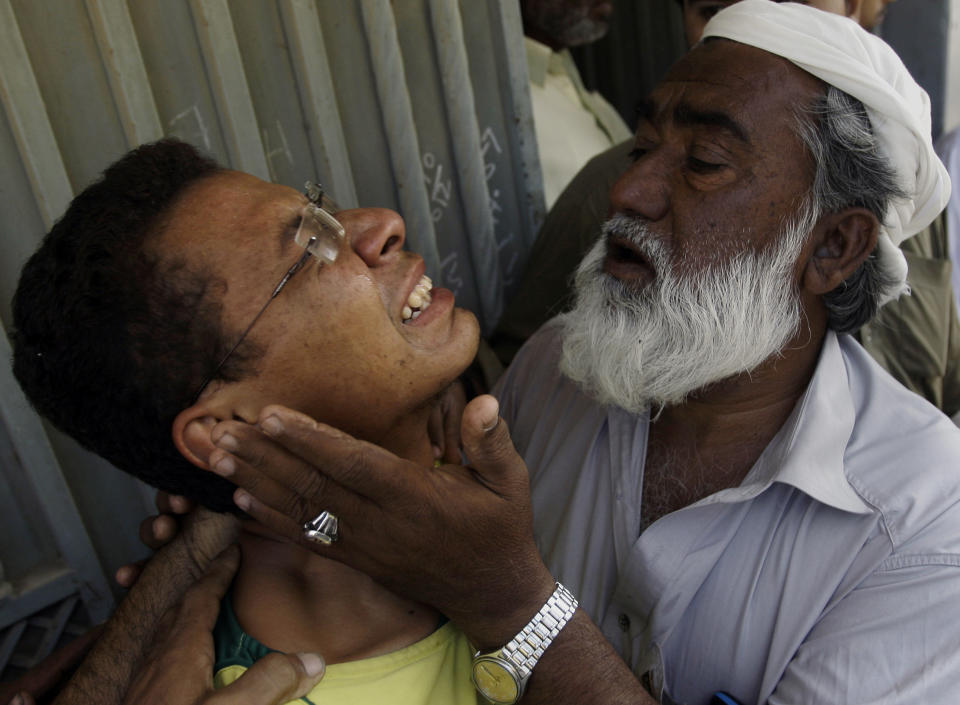 An unidentified man comforts Ali Mohammad, mourning the death of his father killed in a bomb blast, outside his residence in Karachi, Pakistan on Monday, Nov. 26, 2012. A bomb hidden in a cement construction block exploded in the southern city of Karachi killing at least one person and injuring several others, a police official said. (AP Photo/Shakil Adil)
