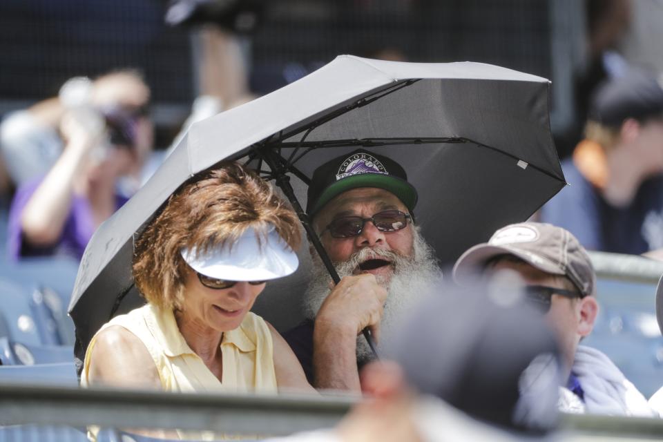 A Colorado Rockies fan uses an umbrella for shade during the third inning of a baseball game against the New York Yankees Saturday, July 20, 2019, in New York. (AP Photo/Frank Franklin II)