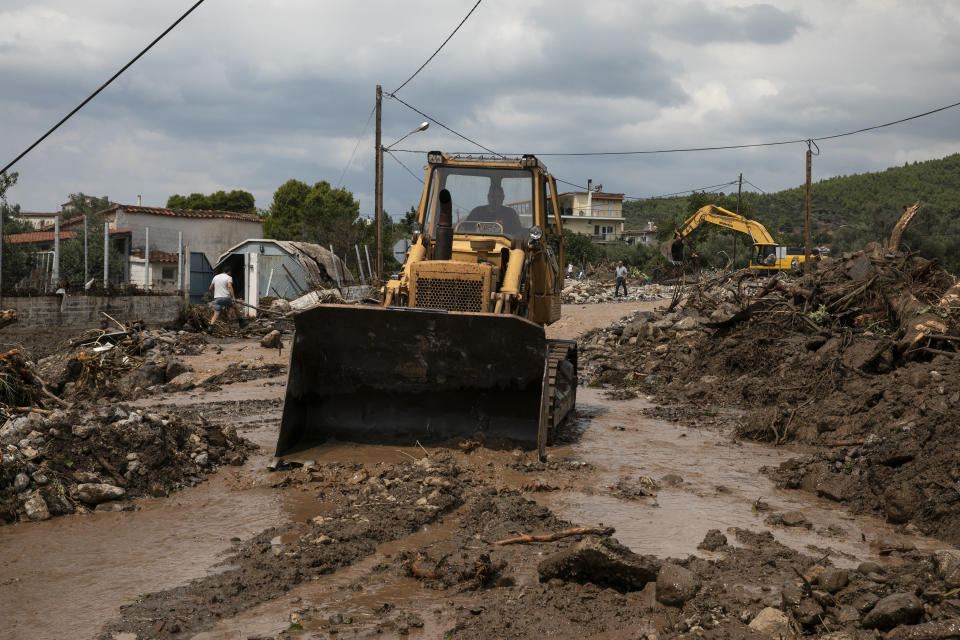 Heavy machinery moves away debris from a destroyed street following a storm at the village of Politika, on Evia island, northeast of Athens, on Sunday, Aug. 9, 2020. An elderly couple and an 8-month-old baby have been found dead and dozens have been trapped in their homes and cars from a storm that has hit the island of Evia, in central Greece, police say. (AP Photo/Yorgos Karahalis)