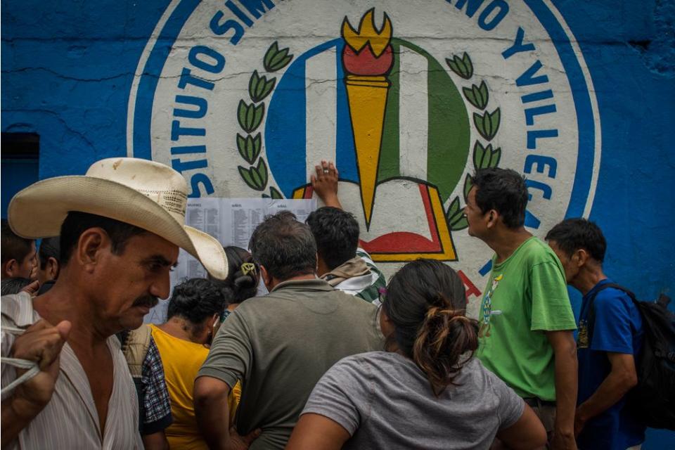 Residents of San Miguel Los Lotes look for relatives' names on a list of survivors at the entrance to a shelter in Escuintla on June 4.