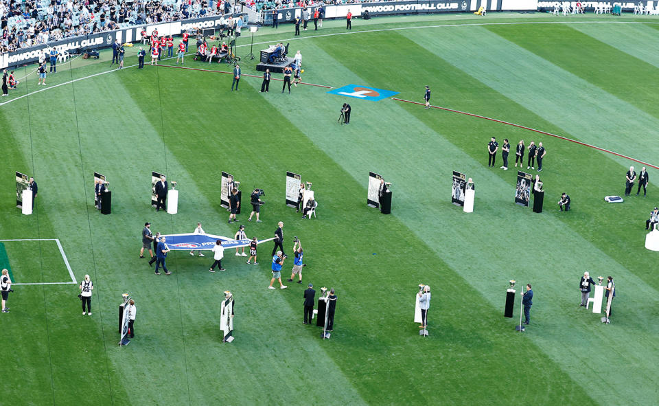 The Magpies with their AFL flag from 2023 and trophies.