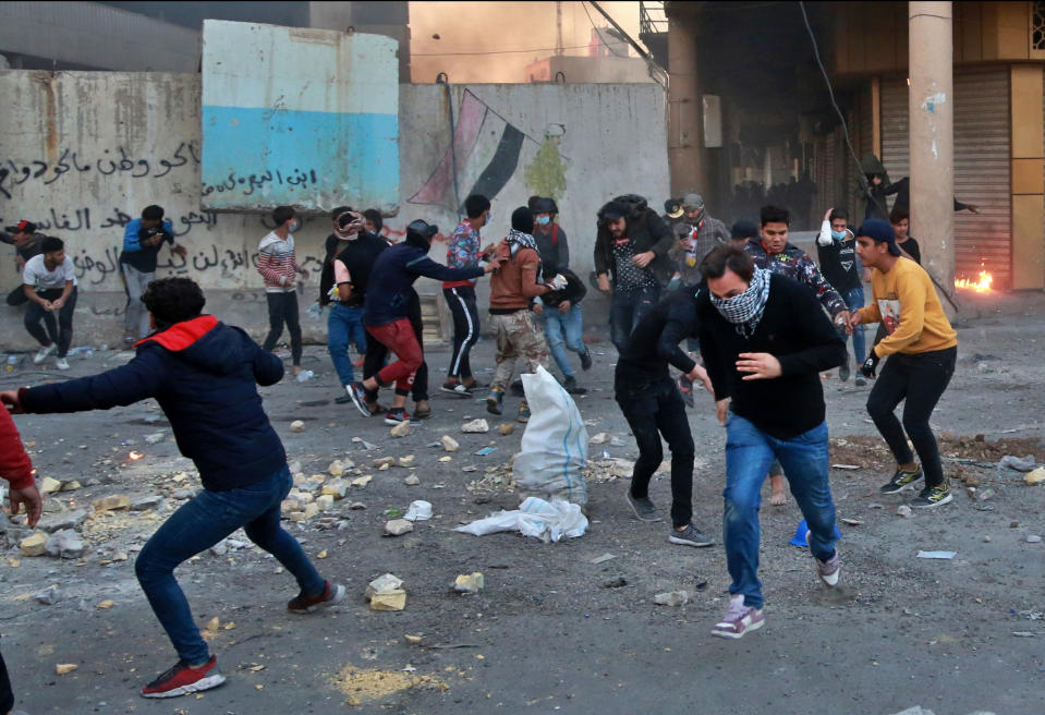 Anti-government protesters run for cover while security forces fire tear gas and live ammunition during clashes between Iraqi security forces and anti-Government protesters, in Baghdad, Iraq, Thursday, Nov. 21, 2019. Iraqi officials said several protesters were killed as heavy clashes erupt in central Baghdad. (AP Photo/Khalid Mohammed)