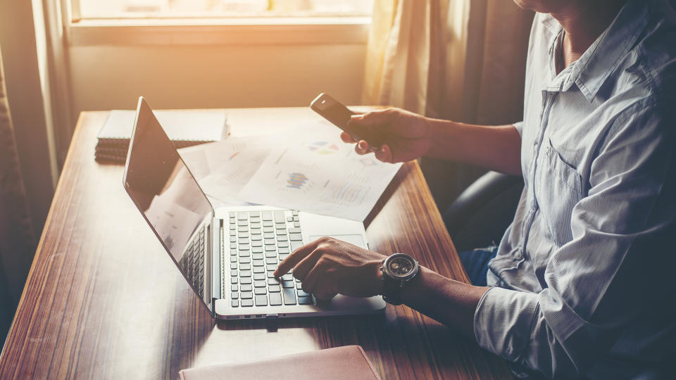 man looking at smartphone and laptop