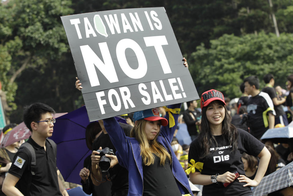 Protesters display a banner denouncing the controversial China Taiwan trade pact during a massive protest in front of the Presidential Building in Taipei, Taiwan, Sunday, March 30, 2014. Over a hundred thousand protesters gathered in a demonstration against the island's rapidly developing ties with the communist mainland. (AP Photo/Wally Santana)