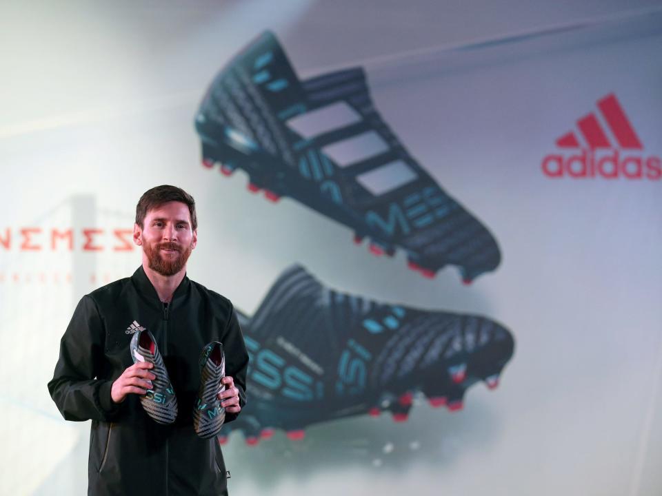 Lionel Messi poses with a pair of cleats at an Adidas event.