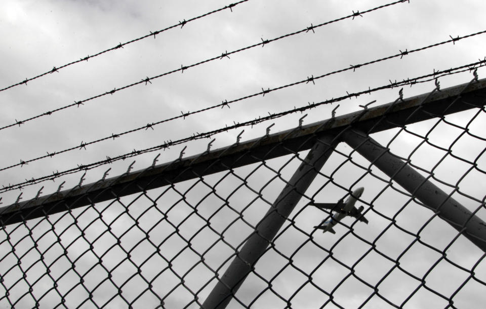 In this Jan. 10, 2013 photo, a plane takes off from the Mariscal Sucre airport, seen behind a gate, in Quito, Ecuador. In addition to the cramped runway and nearby mountains, which force a steep angle of approach, the airport sits at an elevation of nearly 8,700 feet (2,850 meters), an oxygen-thin altitude that diminishes aircraft performance on takeoff and landing. Mariscal Sucre airport sat amid cornfields when it was christened in 1960 and is set to close on Feb. 19. (AP Photo/Dolores Ochoa)