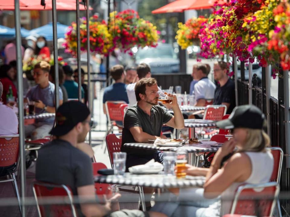 A patron drinks a beverage at a patio in the ByWard Market this summer. Ottawa's planning committee approved a motion to make permanent certain changes to the city's patio rules introduced during the COVID-19 pandemic. (Justin Tang/The Canadian Press - image credit)