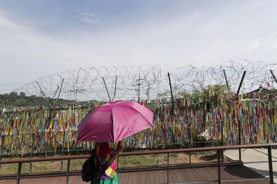A visitor walks near a wire fence decorated with ribbons written with messages wishing for the reunification of the two Koreas at the Imjingak Pavilion in Paju, South Korea, Sunday, Aug. 11, 2019. North Korea said Sunday leader Kim Jong Un supervised test-firings of an unspecified new weapons system, which extended a streak of launches that are seen as an attempt to build leverage ahead of negotiations with the United States while driving a wedge between Washington and Seoul. (AP Photo/Lee Jin-man)