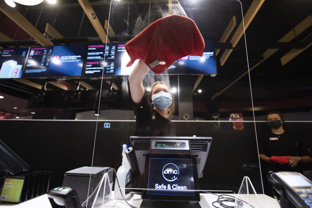 Sara Commarota cleans the plexiglass shield at the AMC Highlands Ranch 24 on August 20, 2020 in Highlands Ranch, Colorado. (Photo by Tom Cooper/Getty Images)