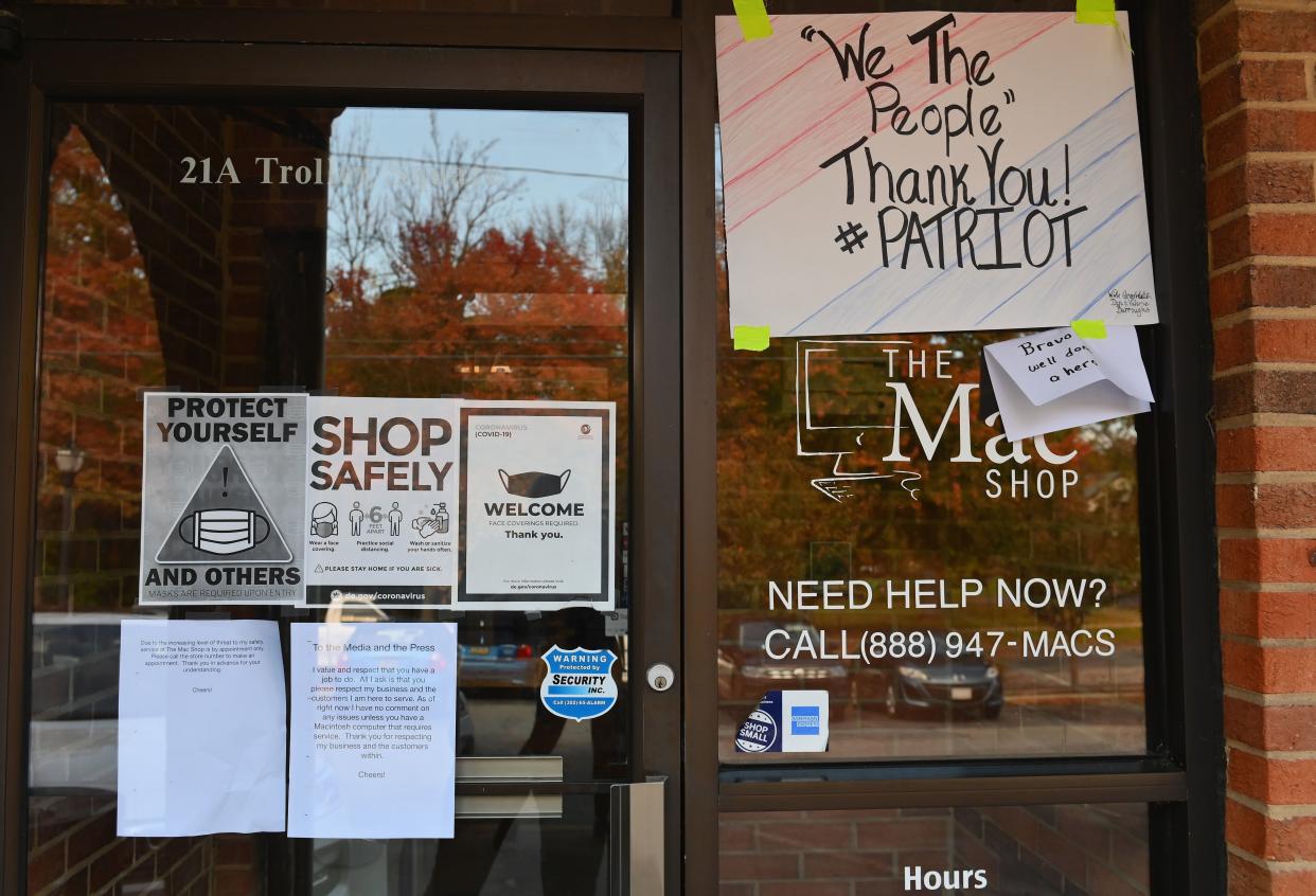 Signs of support are posted on the windows and door of the Mac Shop in Wilmington, Del.