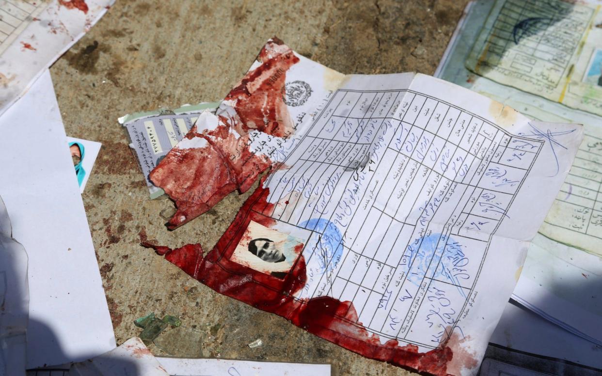 Blood-stained national ID papers of a woman and voters' photos are seen on the ground following the blast  - AP