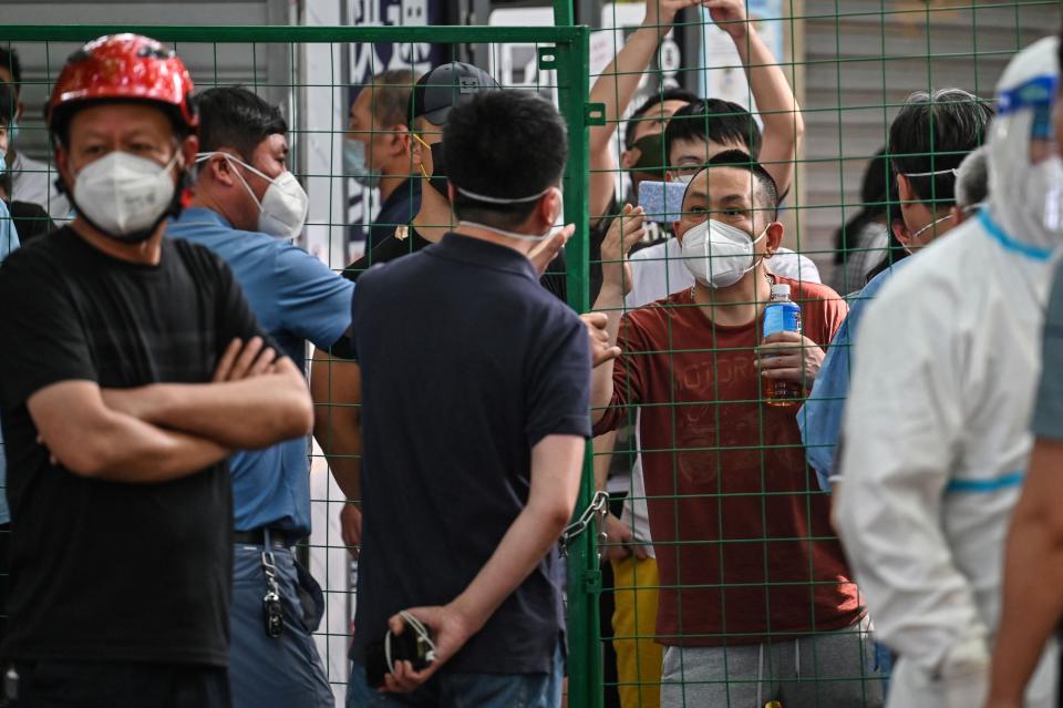Angry residents confront officials from behind a fence erected in a neighbourhood compound in the Xuhui district of Shanghai on June 6, 2022. - Residents stuck inside a compound nearly a week after Shanghai's much vaunted reopening following a virus outbreak shouted at hazmat-clad officials on June 6, as fears grew that some city neighborhoods were being locked down again.