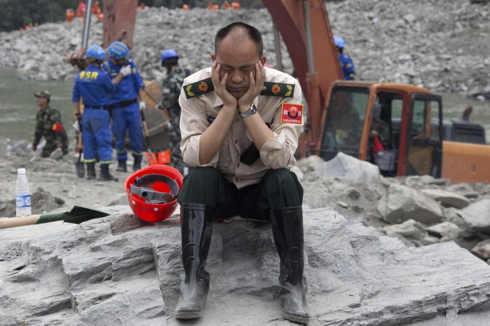 <p>A rescue worker takes a nap at the site of a landslide in Xinmo village in Maoxian County in southwestern China’s Sichuan Province, Sunday, June 25, 2017. Crews searching through the rubble left by a landslide that buried a mountain village under tons of soil and rocks in southwestern China on Saturday found bodies, but more than 100 people remained missing. (Photo: Ng Han Guan/AP) </p>