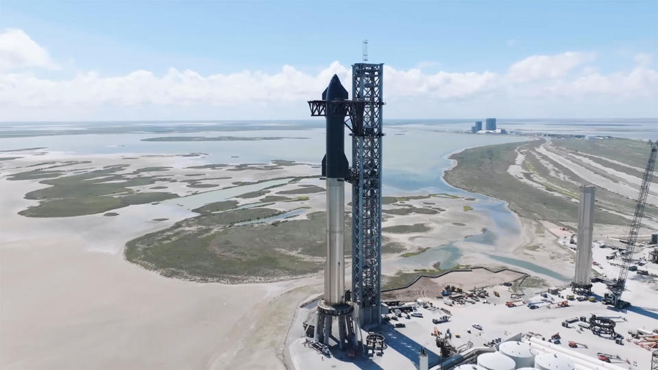 A SpaceX Super Heavy booster (silver) Starship upper stage (black) are seen atop their firing stand at the company's Boca Chica, Texas, flight test facility. The fully-reusable two-stage rocket is the most powerful in the world. / Credit: SpaceX