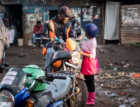 A young girl talks with a boda-boda driver in the Kibera slum - Credit: Simon Townsley/The Telegraph