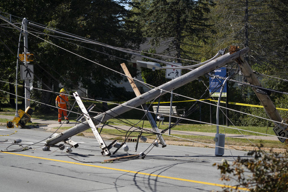 A worker walks past downed power lines and a pole caused by post-tropical storm Fiona in Dartmouth, Nova Scotia, on Sunday, Sept. 25, 2022. Hundreds of thousands of people in Atlantic Canada remain without power and officials are trying to assess the scope of devastation from former Hurricane Fiona. It swept away houses, stripped off roofs and blocked roads across the country’s Atlantic provinces. (Darren Calabrese/The Canadian Press via AP)