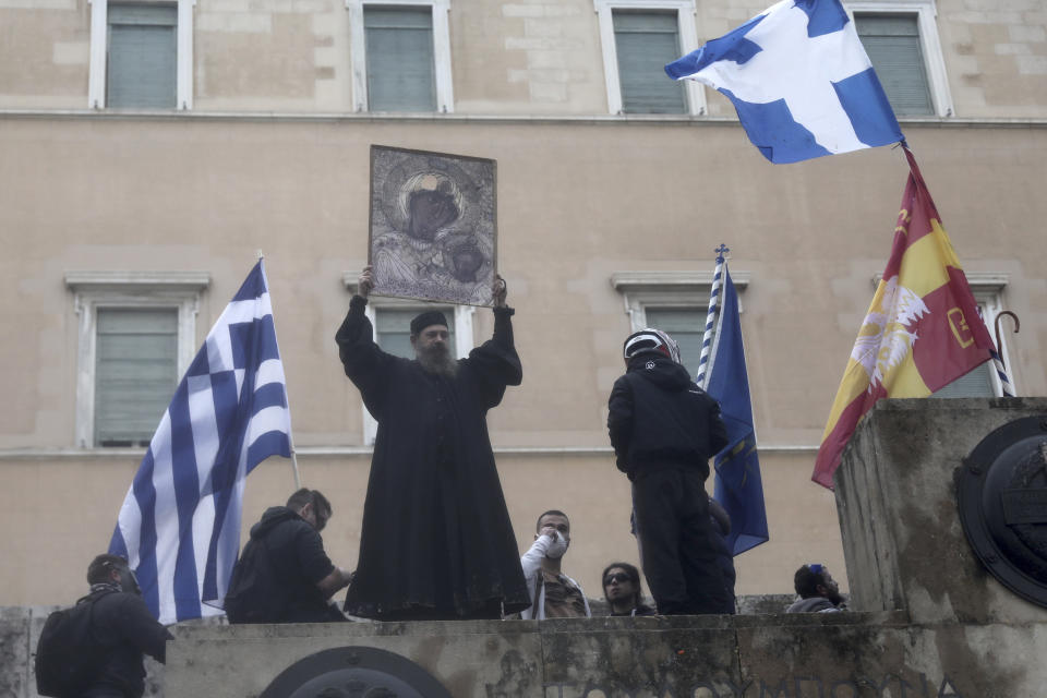 An Orthodox monk holds a representation of the Virgin Mary and child during a clashes in Athens, Sunday, Jan. 20, 2019. Greece's Parliament is to vote this coming week on whether to ratify the agreement that will rename its northern neighbor North Macedonia. Macedonia has already ratified the deal, which, polls show, is opposed by a majority of Greeks. (AP Photo/Yorgos Karahalis)