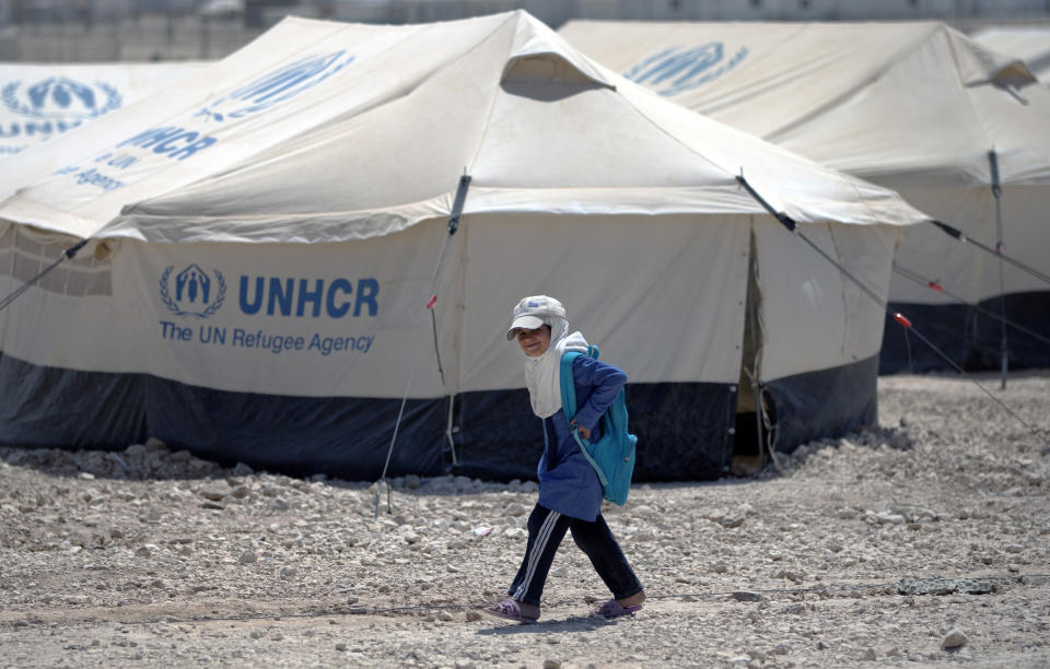 In this Thursday April 17, 2014 photo, a Syrian girl walks past tents on her way back from school at Zaatari refugee camp, near the Syrian border in Jordan. (AP Photo/Khalil Hamra)