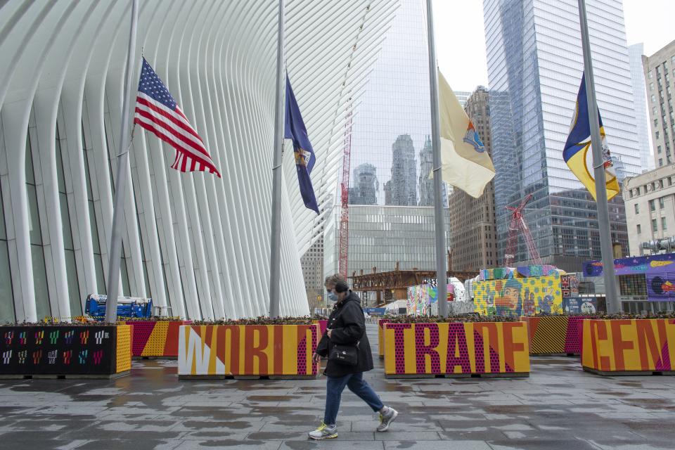 A woman wears a face mask as she passes flags flying at half-mast outside the World Trade Center on April 09, 2020 in New York City.