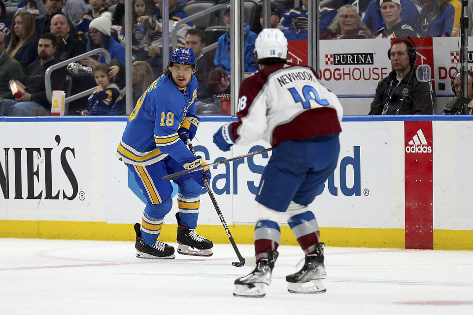 St. Louis Blues' Robert Thomas (18) looks to pass the puck while under pressure from Colorado Avalanche's Alex Newhook (18) during the second period of an NHL hockey game Saturday, Feb. 18, 2023, in St. Louis. (AP Photo/Scott Kane)