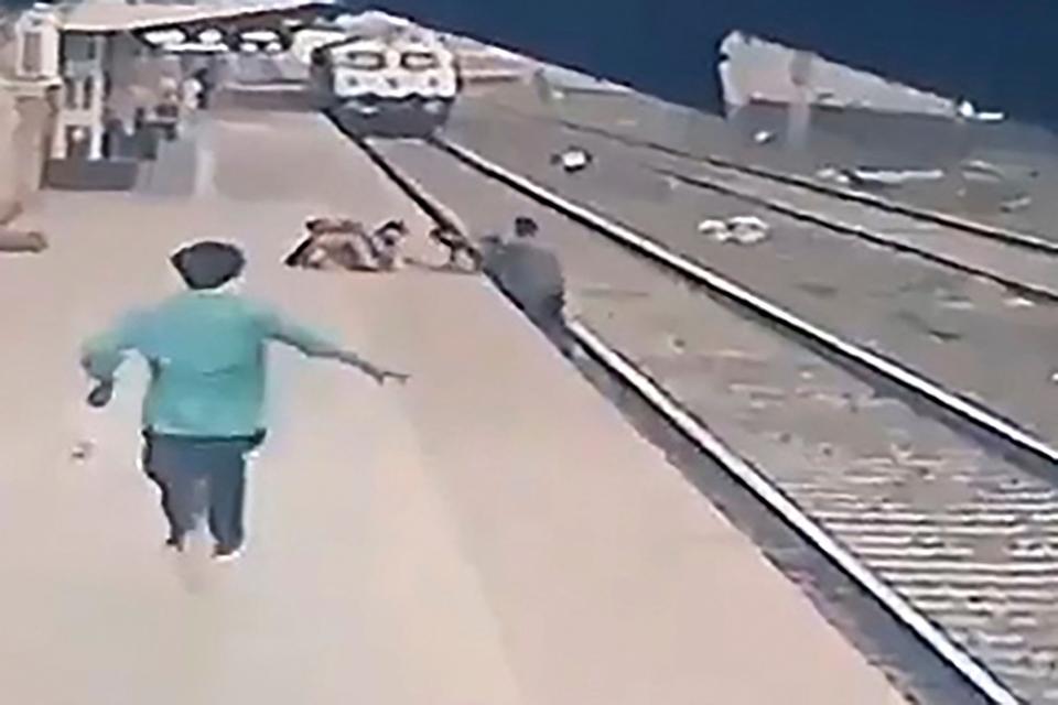 <p>This video frame grab taken from footage released by Indian Ministry of Railways on 20 April, 2021, shows a pointsman (R) saving a child (top C) as he lost his balance and fell in the path of an oncoming train at Vangani railway station in Mumbai</p> (Indian Ministry of Railways /AFP via Getty Images)