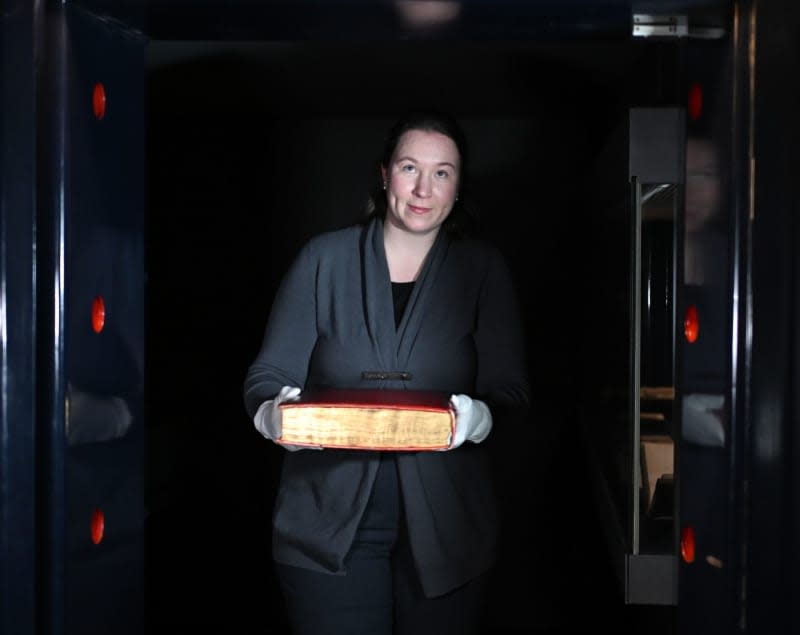 Conservator at the Gutenberg Museum Dorothea Mueller carries the Shuckburgh copy of the Gutenberg Bible from the treasure chamber, which is being digitized in a special device from the company "Microbox" in Bad Nauheim. Arne Dedert/dpa