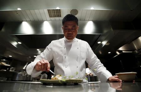 Yoshihiro Narisawa, the owner and chef of Tokyo's French restaurant Narisawa, prepares a dish for an early spring menu which includes charcoal grilled fugu, or tiger pufferfish, from Hagi, a city in western Japan, accompanied with grilled pufferfish testes, at the kitchen of Narisawa in Tokyo March 26, 2015. REUTERS/Yuya Shino