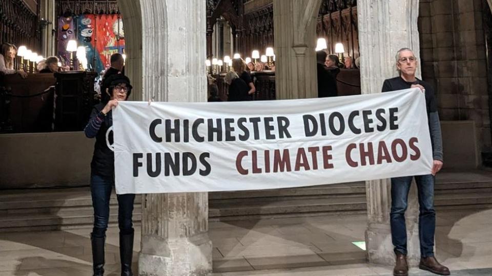 Climate protesters holding a banner that reads: Chichester Diocese funds climate chaos