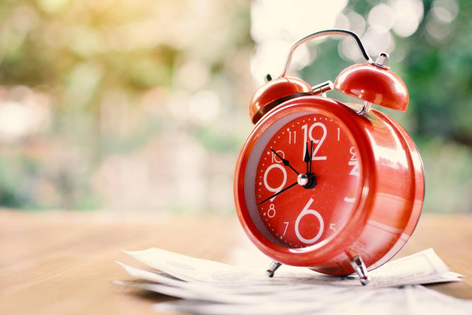 red alarm clock sitting on papers on a brown table