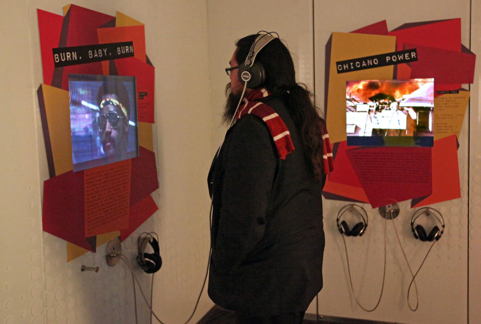 This March 26, 2012 photo shows a visitor listening to music and spoken word recordings at an interactive exhibit about the 1965 Watts Riots at "Trouble In Paradise: Music and Los Angeles, 1945-1975," at the Grammy Museum in downtown Los Angeles. The museum website says the exhibit focuses on the "tensions between alluring myths of Southern California paradise and the realities of social struggle that characterized the years following WWII." (AP Photo/Reed Saxon)