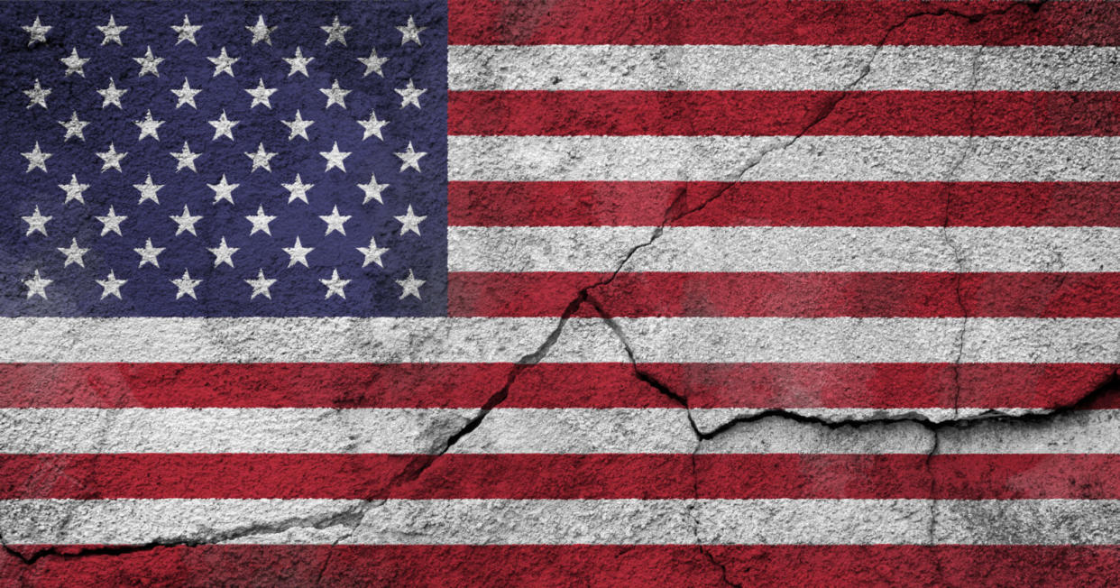 weathered American flag painted on a cracked wall - Other countries issue US travel warnings