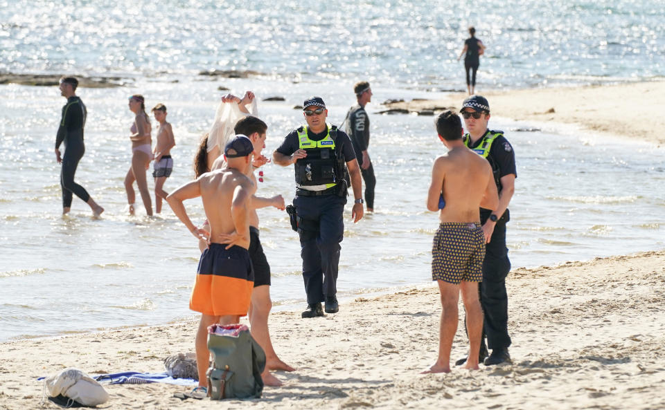 Police officers inform beachgoers that the Brighton Beach is closed as on-the-spot fines for people who breach social distancing rules during coronavirus