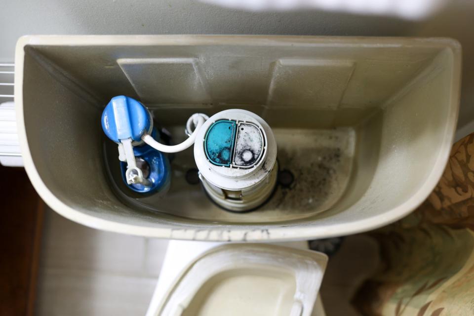 a broken toilet with black mold in tank