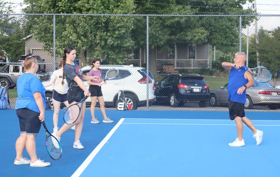 Cambridge High School Tennis Coach Tim Gibson gives instructions to some of his Lady Bobcat players during a open court workout session on the newly resurfaced tennis courts at Cambridge City Park.