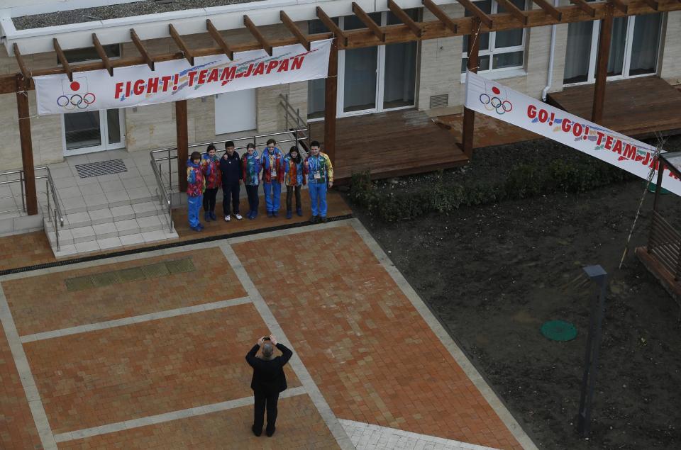 Volunteers pose outside the apartments in the Coastal Village where athletes will reside during the 2014 Winter Olympics, Wednesday, Jan. 29, 2014, in Sochi, Russia. (AP Photo/Pavel Govolkin)