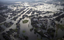 FILE - In this Aug. 31, 2017, file photo, floodwaters from Tropical Storm Harvey surround homes in Port Arthur, Texas. Many Texas families are still struggling to recover from Hurricane Harvey, a year after it caused widespread damage and flooding along the Gulf Coast and in and around Houston. But daily life has mostly returned to normal in many of the hardest hit communities. (AP Photo/Gerald Herbert, File)