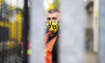 Steward Thorsten Lange stands behind the locked stadium gates at Signal Iduna Park with a BVB mask prior to the German Bundesliga soccer match between Borussia Dortmund and FC Schalke 04 in Dortmund, Germany, Saturday, May 16, 2020. The German Bundesliga becomes the world's first major soccer league to resume after a two-month suspension because of the coronavirus pandemic. (Guido Kirchner/dpa via AP)