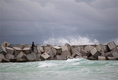 A man fishes while standing on wave breakers in Cancun October 3, 2013. REUTERS/Victor Ruiz Garcia