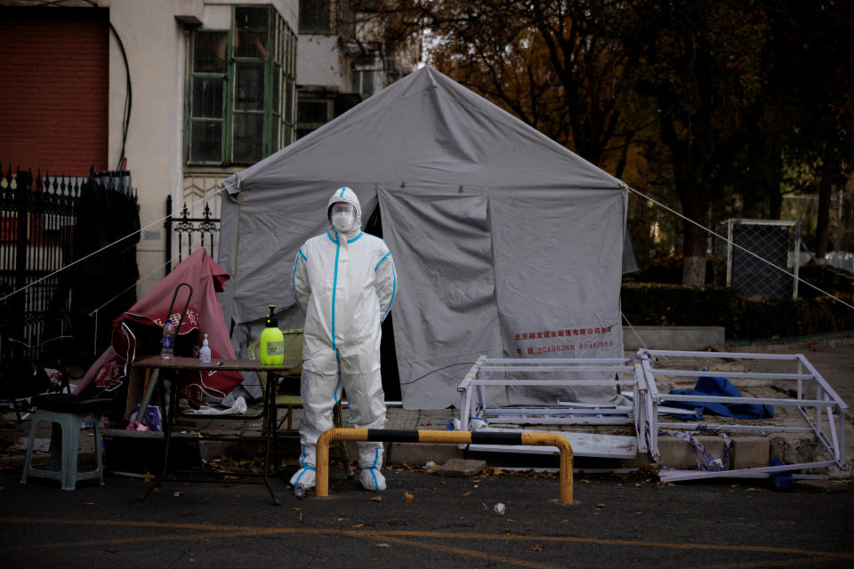 Pracovník prevence pandemie v ochranném obleku stojí před bytovým komplexem, který byl uzavřen, protože epidemie koronavirové nemoci (COVID-19) pokračují v Pekingu, Čína, 12. listopadu 2022. REUTERS/Thomas Peter