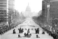 The motorcade bearing President Johnson to the Capitol for his inauguration moves along Pennsylvania Avenue, January 20, 1965. Police on motorcycles lead the way. (AP Photo)