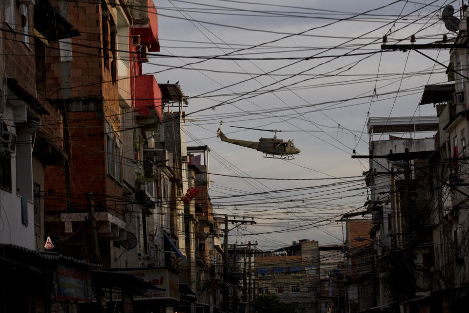 A police helicopter flies over the Mare slum complex during it's occupation in Rio de Janeiro, Brazil, Sunday, March 30, 2014. The Mare complex of slums, home to about 130,000 people and located near the international airport, is the latest area targeted for the government's "pacification" program, which sees officers move in, push out drug gangs and set up permanent police posts. (AP Photo/Silvia Izquierdo)