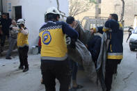 This photo provided by the Syrian Civil Defense White Helmets, which has been authenticated based on its contents and other AP reporting, shows Syrian White Helmet civil defense workers carrying a casualty, in the northern town of Ariha, in Idlib province, Syria, Wednesday, Oct. 20, 2021. Rescue workers reported several people were killed, including children and a woman, in shelling by Syrian government forces on Ariha, in the last rebel enclave in the country's northwest. (Syrian Civil Defense White Helmets via AP)