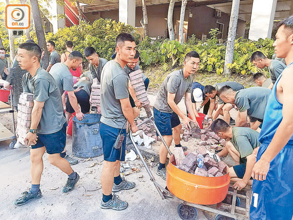 駐港解放軍官兵合力清理路面的磚頭，並搬到馬路旁。