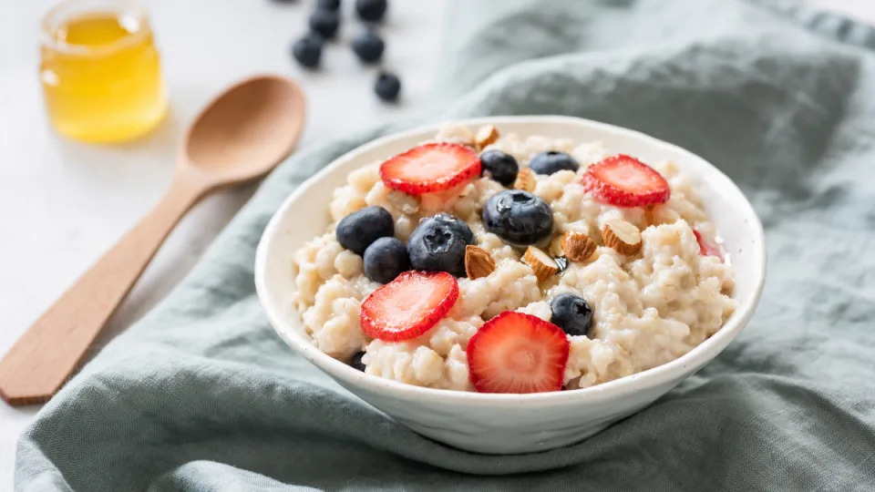 A bowl of oatmeal with fresh blueberries and strawberries set on a dish towel